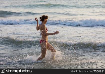 Beautiful young girl jumping on sea