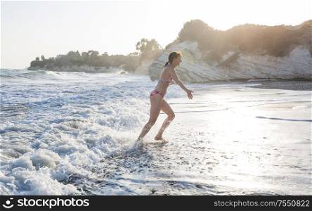Beautiful young girl jumping on sea