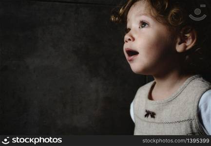 Beautiful young girl looking away against a dark moody background
