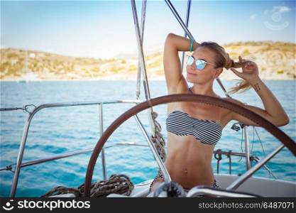 Beautiful young girl traveling along Mediterranean sea on sail boat, attractive model posing on the deck of sailboat for summer photoshoot, enjoying active summertime holidays. Beautiful girl on sail boat