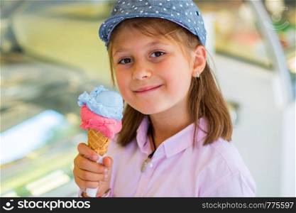 beautiful young girl with hat eating an ice cream outdoors