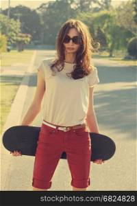 Beautiful young girl with skateboard in the evening light with vintage instagram style toning