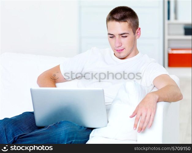 beautiful young guy looks in the laptop at home