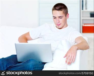 beautiful young guy looks in the laptop at home