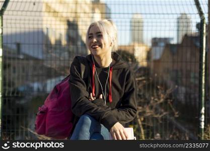 Beautiful young happy smiling woman against the background of a European city in the sun at sunset, student and traveler, vacation in the city