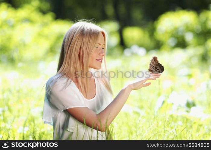 Beautiful young happy Woman playing with butterfly outdoors