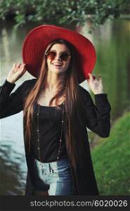 Beautiful young hippie girl outdoors enjoying nature. Trendy boho fashion Caucasian woman wearing black cardigan, hat and denim jeans.