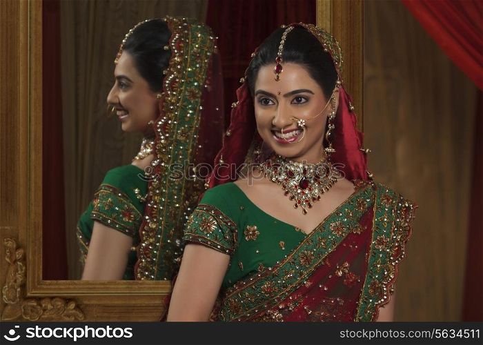 Beautiful young Indian bride standing in front of mirror