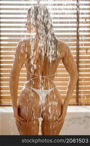 Beautiful young lady bikini model with perfect slim body in shower. Back view copped shot. Beautiful young lady in shower back view