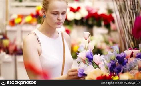 Beautiful young lady buying fresh flowers in a store or market choosing blooms for her decor at home