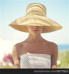 Beautiful young lady in straw hat in the sunlight