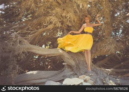 Beautiful young lady in yellow dress with mighty tree
