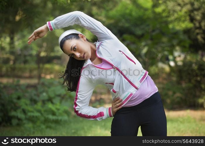 Beautiful young lady stretching in park