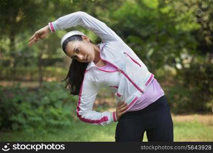 Beautiful young lady stretching in park