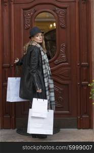 beautiful young lady , with hat and scarf , coming back home after shopping , she bring some shopper , she looking in camera