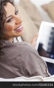 Beautiful young Latina Hispanic woman laughing, relaxing and using a tablet computer