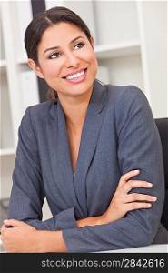 Beautiful young Latina Hispanic woman or business woman smiling and relaxing in her office