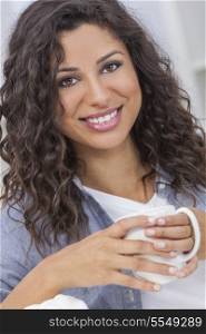 Beautiful young Latina Hispanic woman smiling and happy at home drinking a cup of tea or coffee