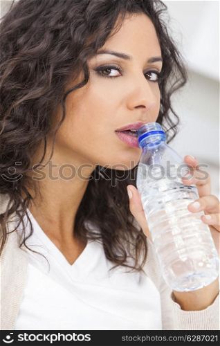 Beautiful young Latina Hispanic woman smiling, relaxing and drinking a bottle of water