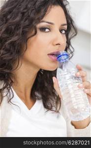 Beautiful young Latina Hispanic woman smiling, relaxing and drinking a bottle of water