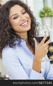 Beautiful young Latina Hispanic woman smiling, relaxing and drinking a glass of red wine