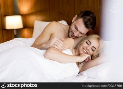 Beautiful young loving couple lying on bed in the room