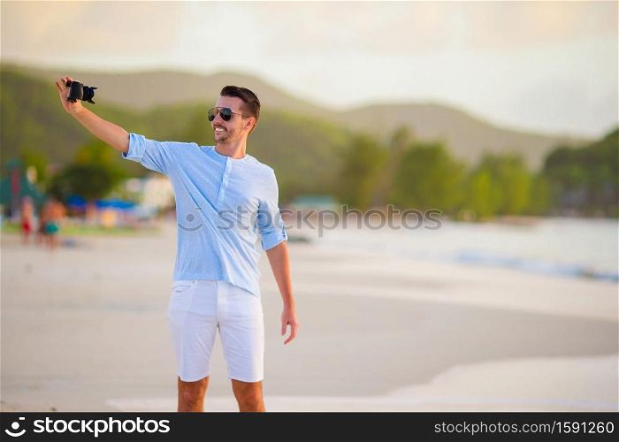 Beautiful young man taking a photo herself on tropical beach. Beautiful young man taking a self photo herself on tropical beach