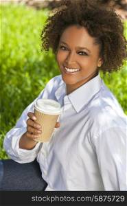 Beautiful young mixed race black African American woman with perfect teeth, smiling, drinking coffee or tea outside in a park &amp; summer sunshine