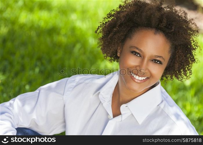 Beautiful young mixed race black African American woman with perfect teeth smiling and relaxing outside in summer sunshine