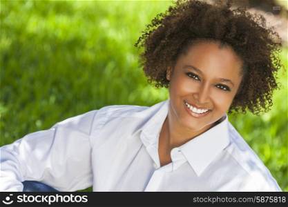 Beautiful young mixed race black African American woman with perfect teeth smiling and relaxing outside in summer sunshine