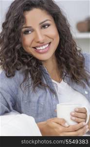 Beautiful young mixed race Latina Hispanic woman smiling, relaxing and drinking a cup of coffee or tea