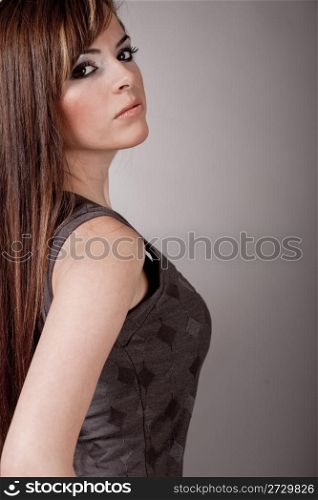 Beautiful young model leaning on a wall on a light background