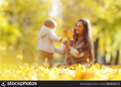 Beautiful young mother and her daughter in autumn park