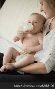 Beautiful young mother feeding with milk her cute baby boy
