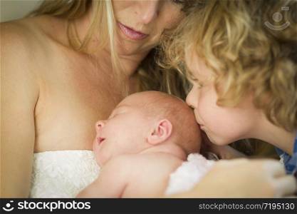 Beautiful Young Mother Holds Newborn Baby Girl as Brother Kisses Her Head.