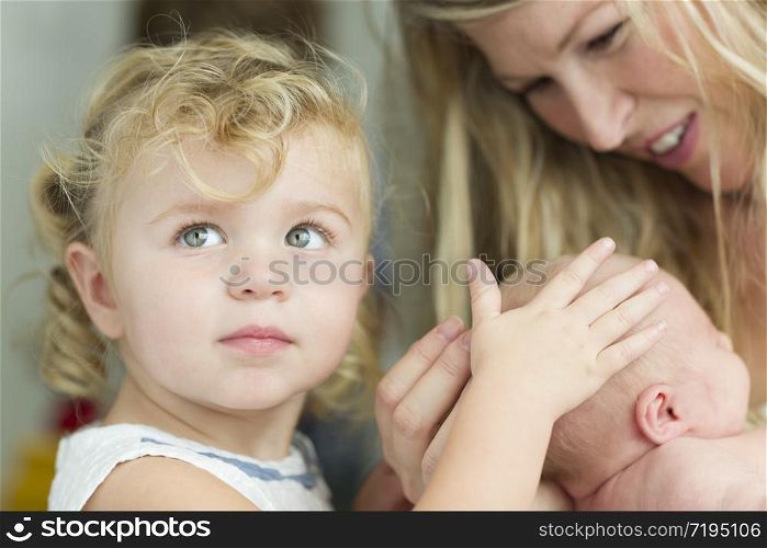 Beautiful Young Mother Holds Newborn Baby Girl as Young Sister Looks On.