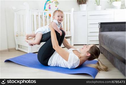 Beautiful young mother practicing yoga with her baby boy