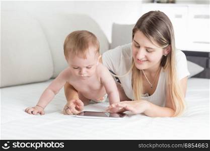 Beautiful young mother teaching her baby boy how to tablet computer