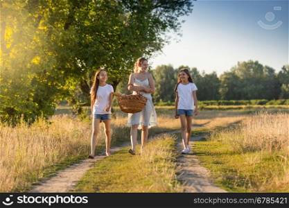 Beautiful young mother walking to picnic with her two daughter