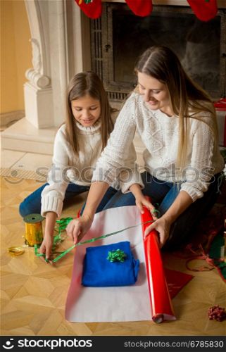 Beautiful young mother wrapping Christmas presents with her daughter