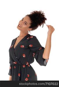 Beautiful young multi-racial woman standing waist up in a black dress with floral print playing with her black hair in a bun on top ofher head, smiling, isolated for white background