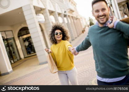 Beautiful young multiethnic couple with paper bags enjoying in shopping and having fun in the city