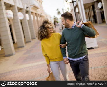 Beautiful young multiethnic couple with paper bags enjoying in shopping and having fun in the city