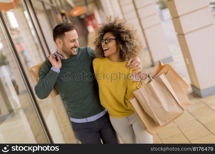 Beautiful young multiethnic couple with paper bags enjoying in shopping, having fun in the city