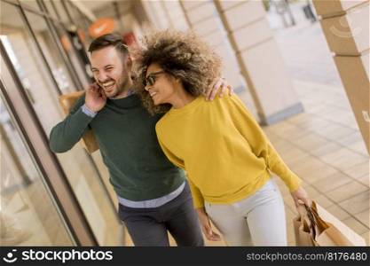 Beautiful young multiethnic couple with paper bags enjoying in shopping, having fun in the city