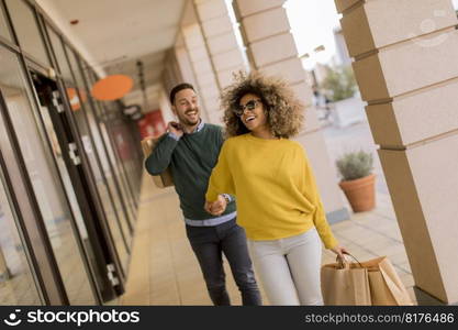 Beautiful young multiethnic couple with paper bags enjoying in shopping, having fun in the city