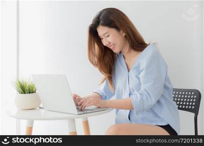 Beautiful young of Asian woman using a laptop while sitting working at home, Asia women smile while typing work from home