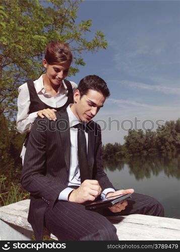 Beautiful young people using PDA outdoors