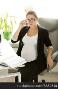 Beautiful young pregnant businesswoman talking on phone at working place