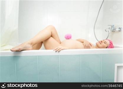 Beautiful young pregnant woman lying in bath